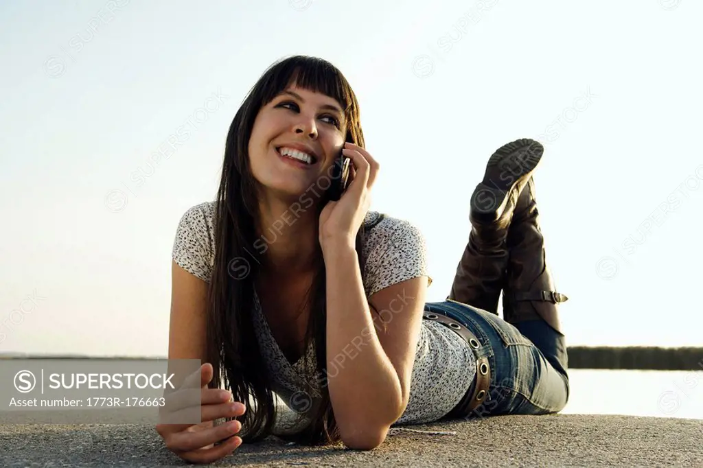Girl talking on mobile phone by lake