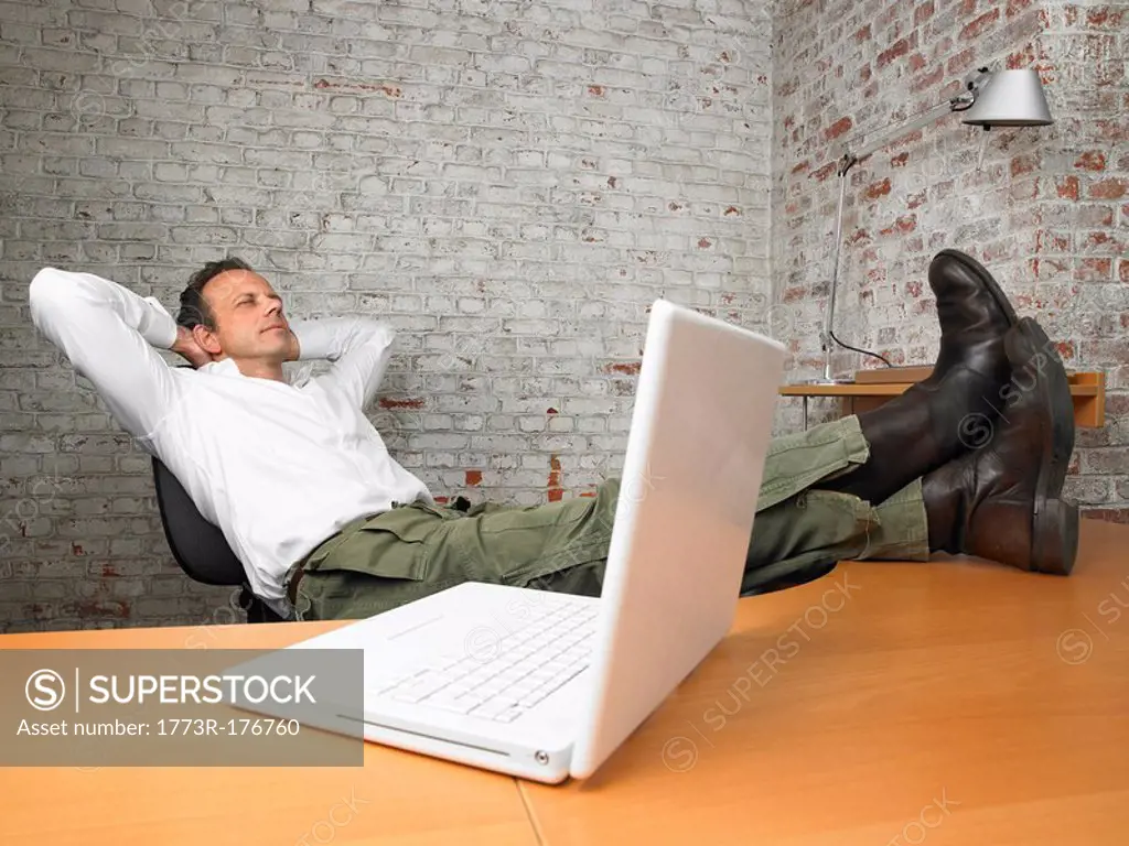 Businessman resting with feet on desk ,
