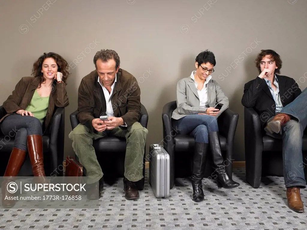 Two businesswomen and two businessmen sitting in waiting room