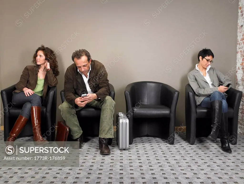 Two businesswomen and a businessman sitting in waiting room