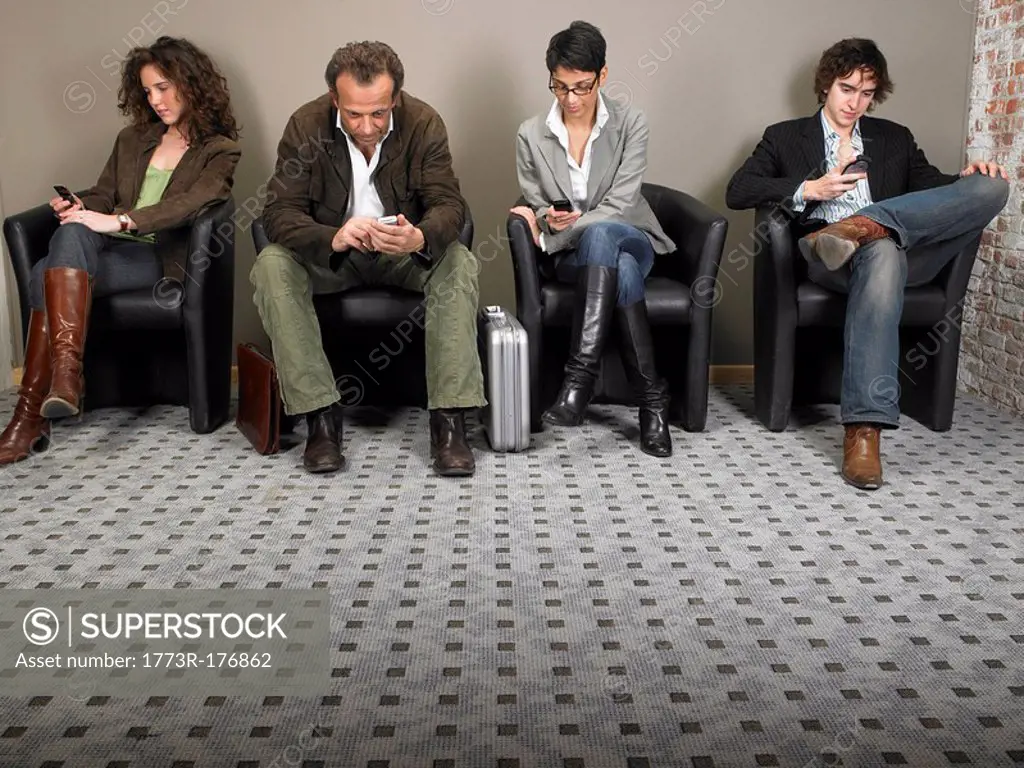 Two businesswomen and two businessmen sitting in waiting room