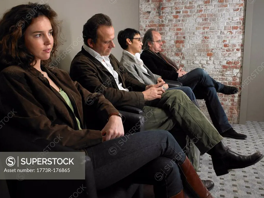 Two businesswomen and two businessmen sitting in waiting room, side view