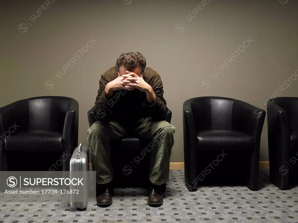 Anxious businessman in waiting room, head in hands