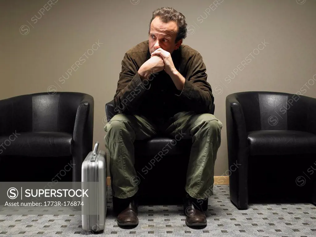 Mature businessman sitting in waiting room, resting chin on hands