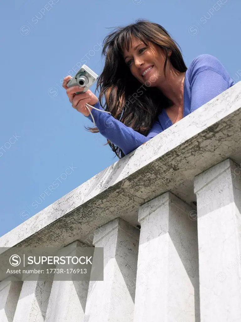 Woman on balcony taking photograph with digital camera Venice, Italy