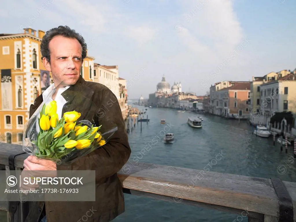 Italy, Venice, man waiting on bridge holding flowers