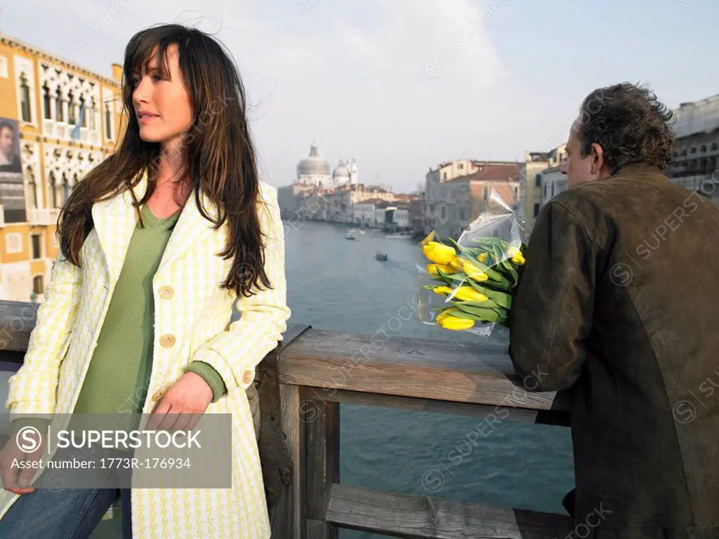 Woman and man with flowers on Academia Bridge overlooking Grand Canal Venice, Italy