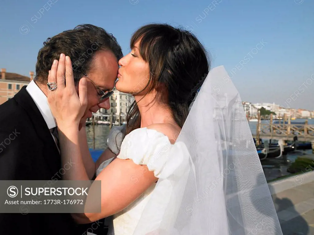 Bride kissing groom´s forehead Grand Canal, Venice, Italy