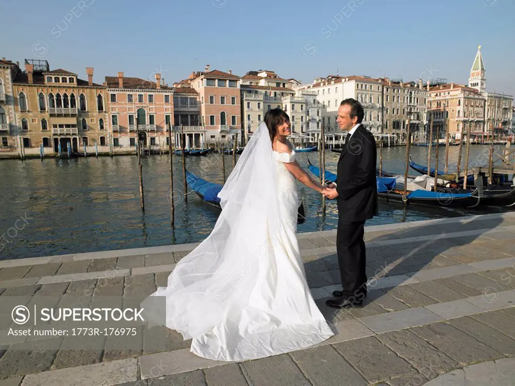 Bride and groom holding hands Grand Canal, Venice, Italy