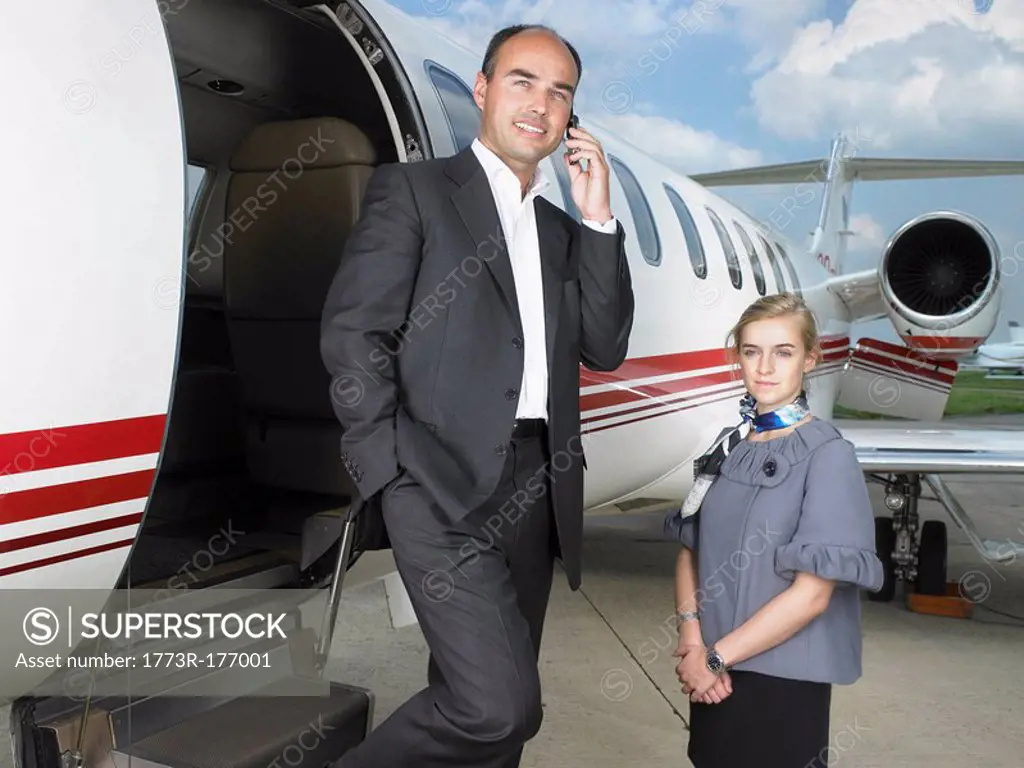 Businessman exiting private jet next to flight attendant