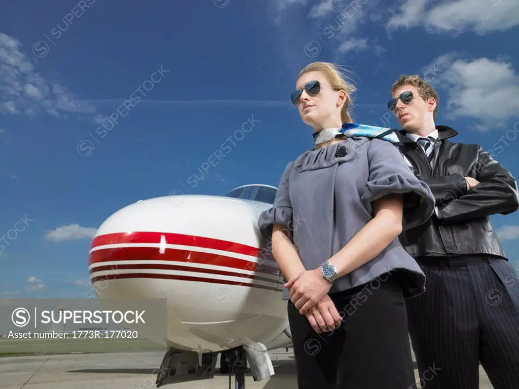 Pilot and flight attendant standing in front of private jet