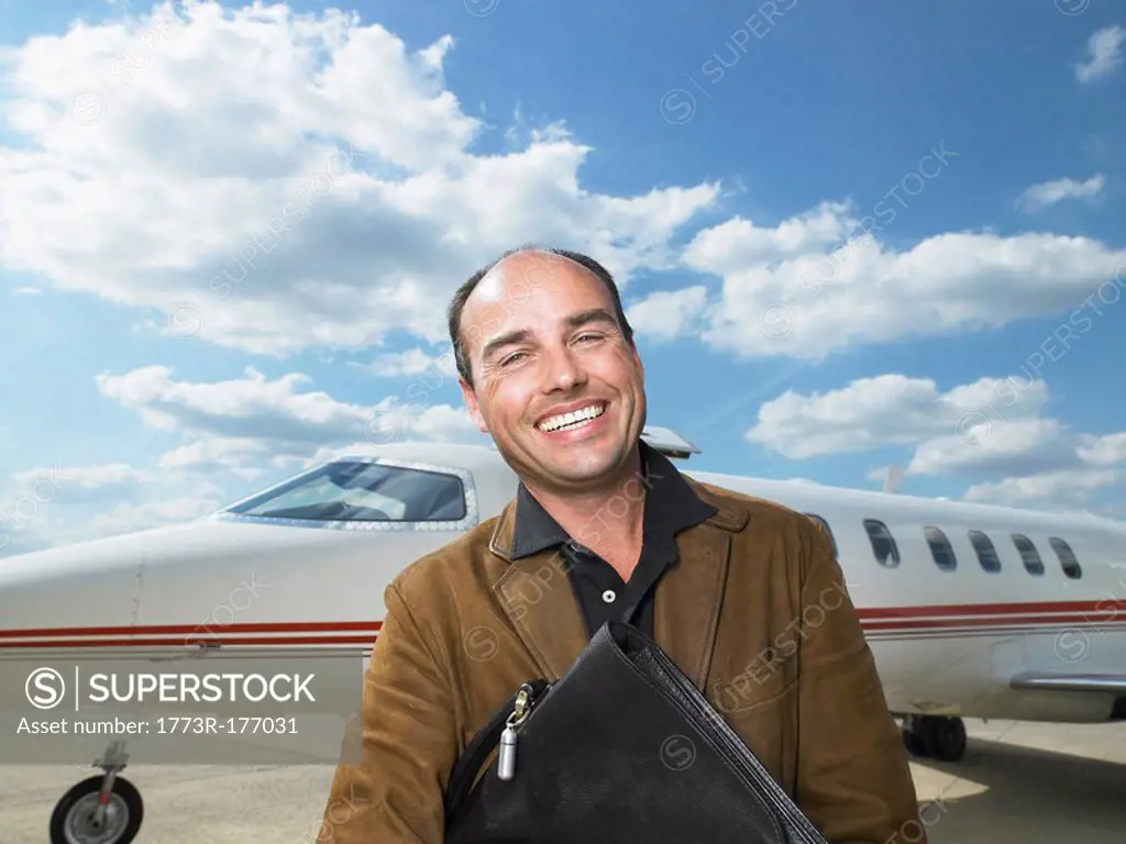 Smiling man standing next to private jet
