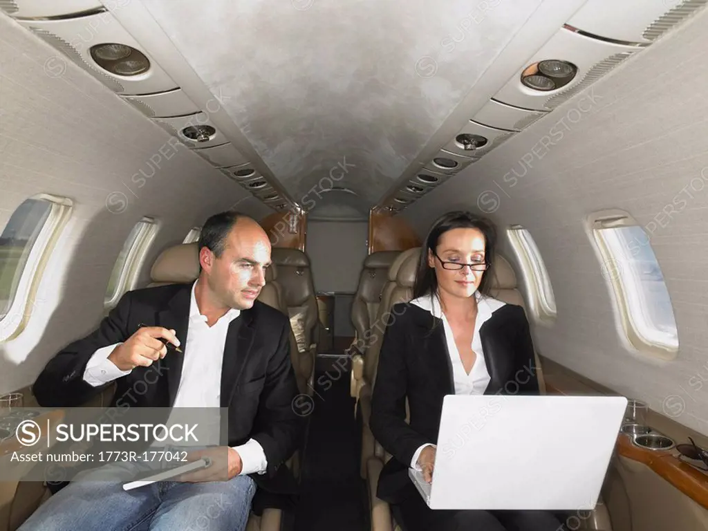 Businesswoman and businessman in private jet having a discussion