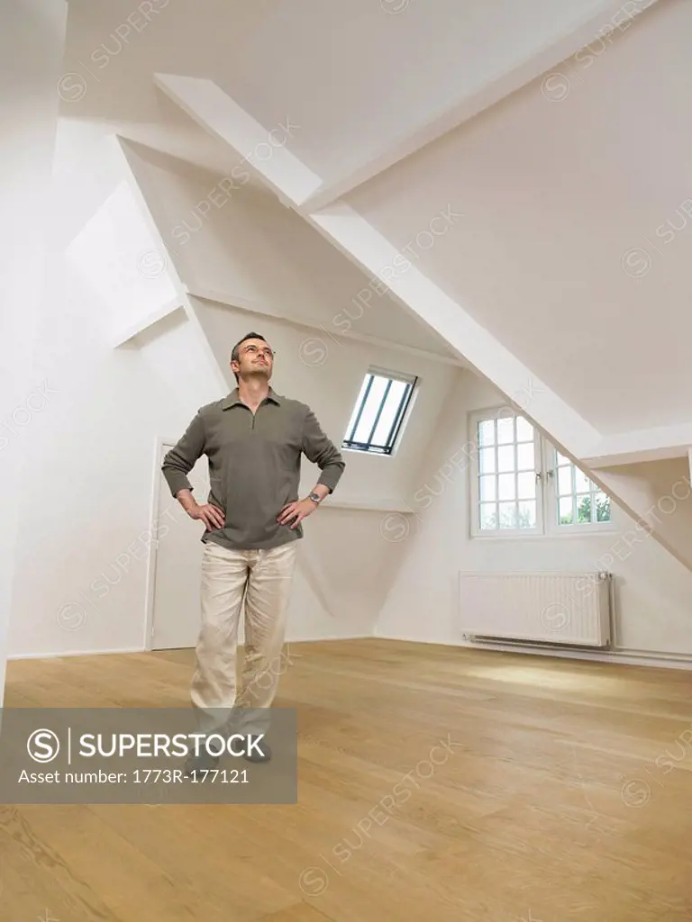 Man looking up inside empty white loft