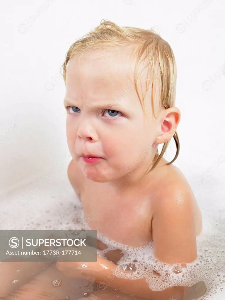 Little girl taking a bath making a face