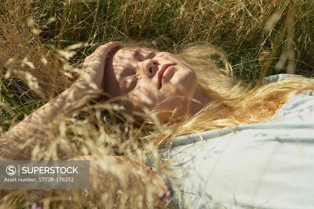 Young woman lying in long grass