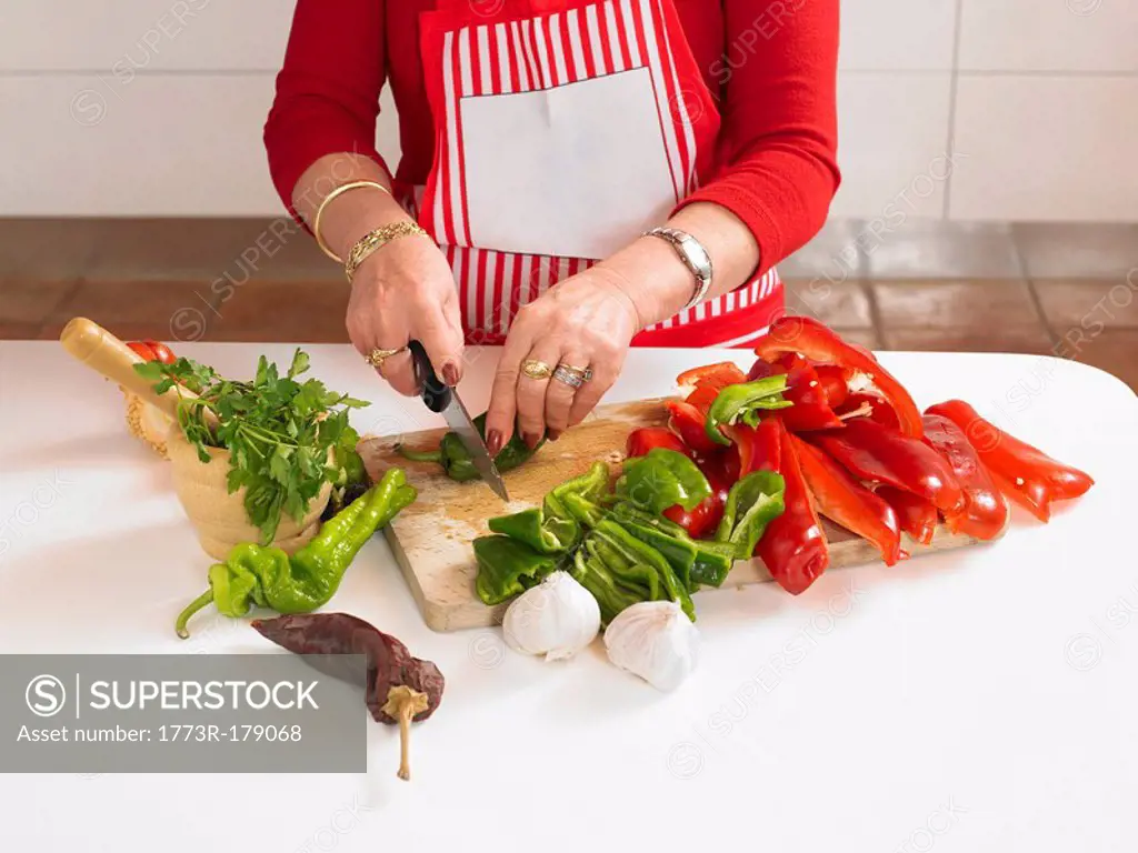 Mature woman chopping vegetables in kitchen, mid section