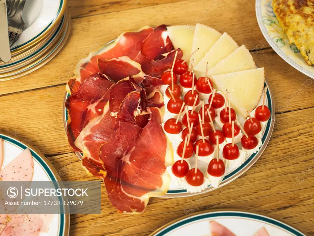 Plate of cured ham and cheese on table, close-up