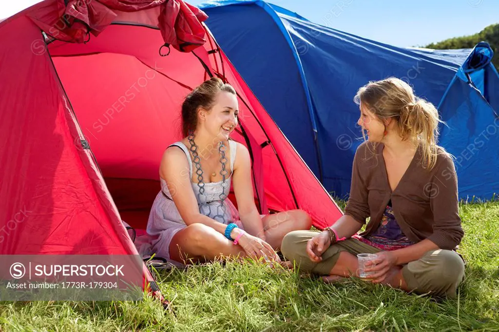Two girls sitting by tents