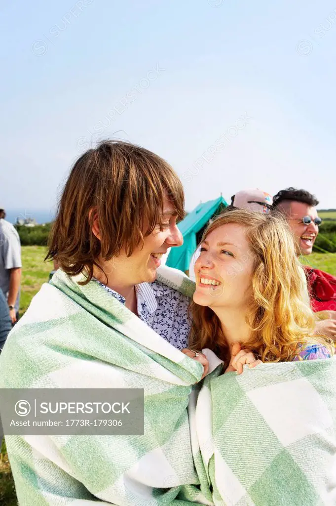 Couple wrapped in blanket looking at each other