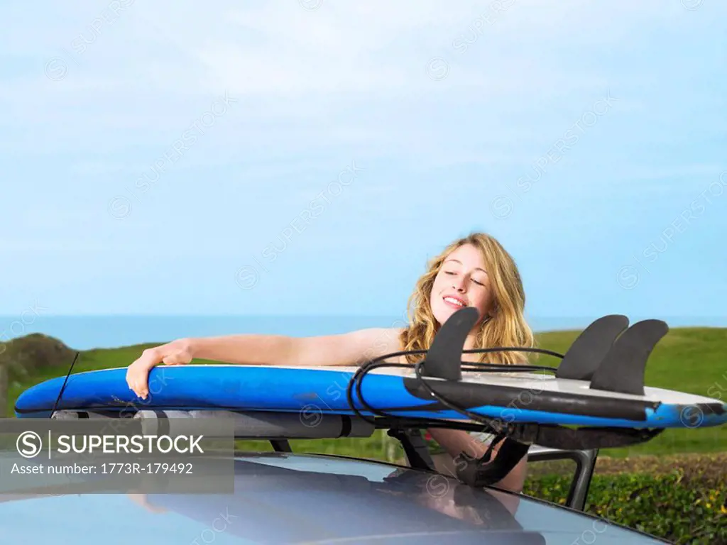 Female taking surfboard off car roof