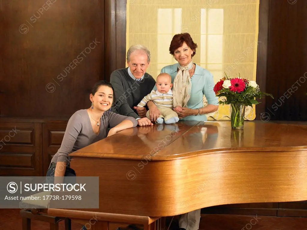 Multigenerational family grandparents, mother and baby son 7months by grand piano, portrait Alicante, Spain