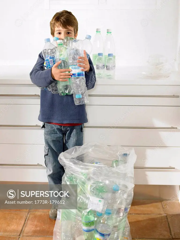 Young boy holding an armful of recyclable plastic bottles, portrait
