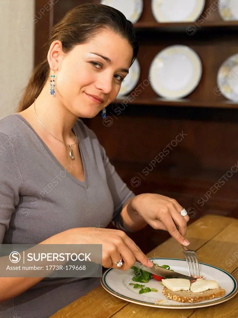 Young woman eating lunch, smiling, portrait