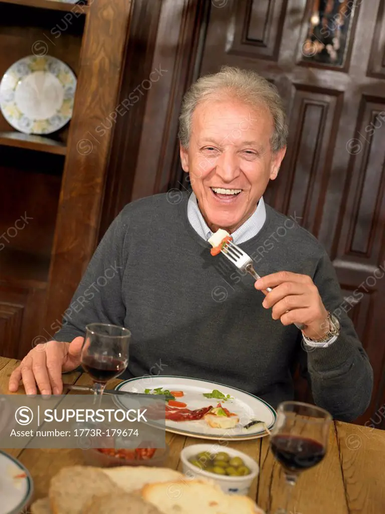 Senior man eating lunch, smiling, portrait