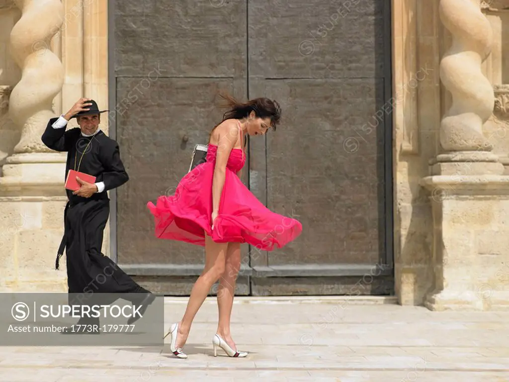Priest passing woman whose skirt is blowing up in the wind, Alicante, Spain,
