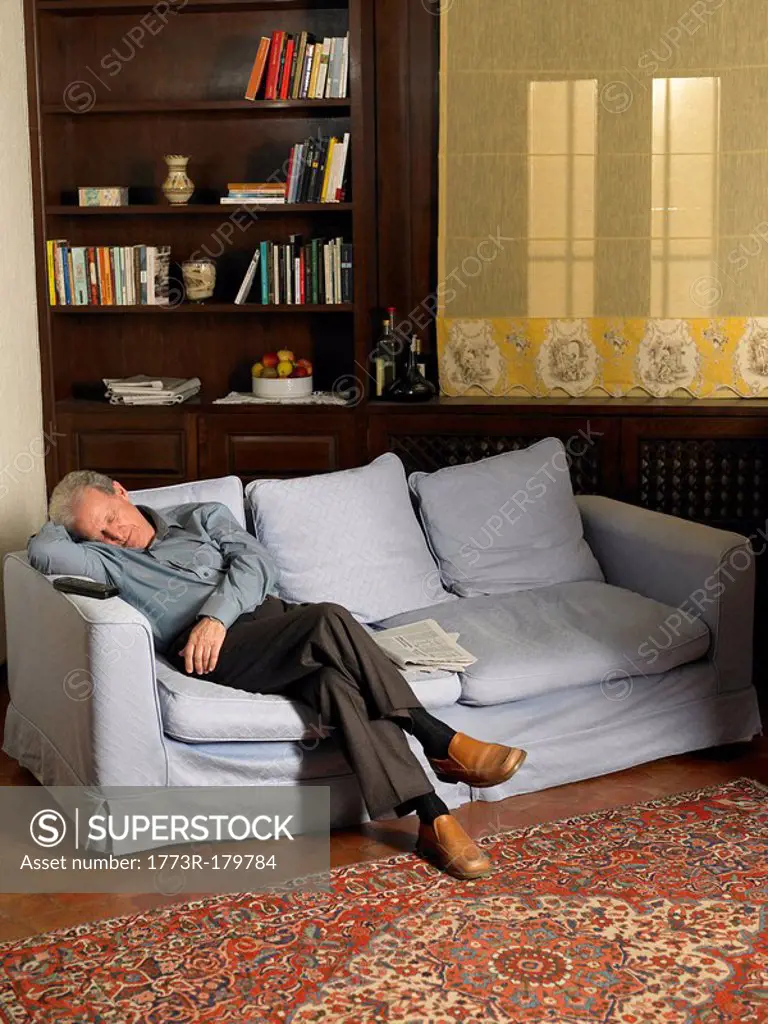 Senior man asleep on sofa in living room