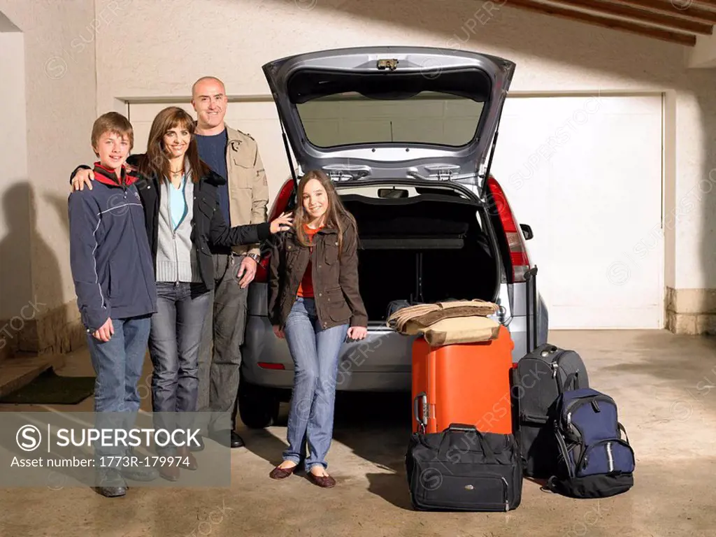 Family standing by car and luggage, portrait