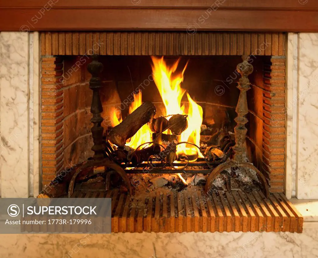 Log fire burning in fireplace with red brick surround