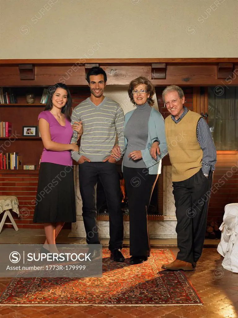 Young couple and senior couple standing in living room, smiling, portrait