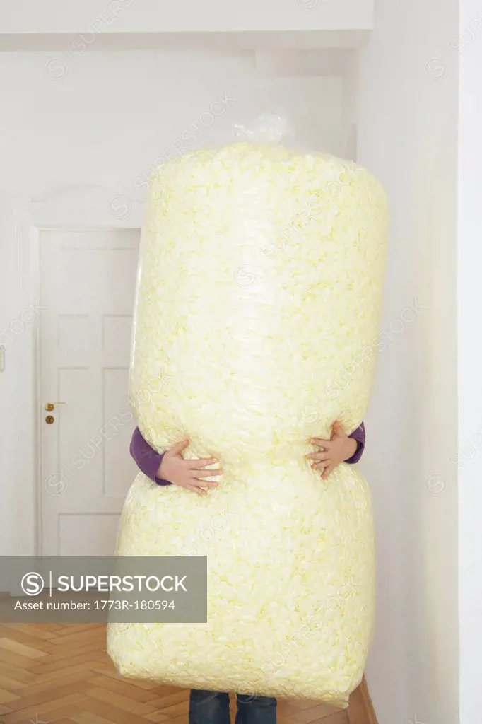 Young woman carrying large bag of packing foam