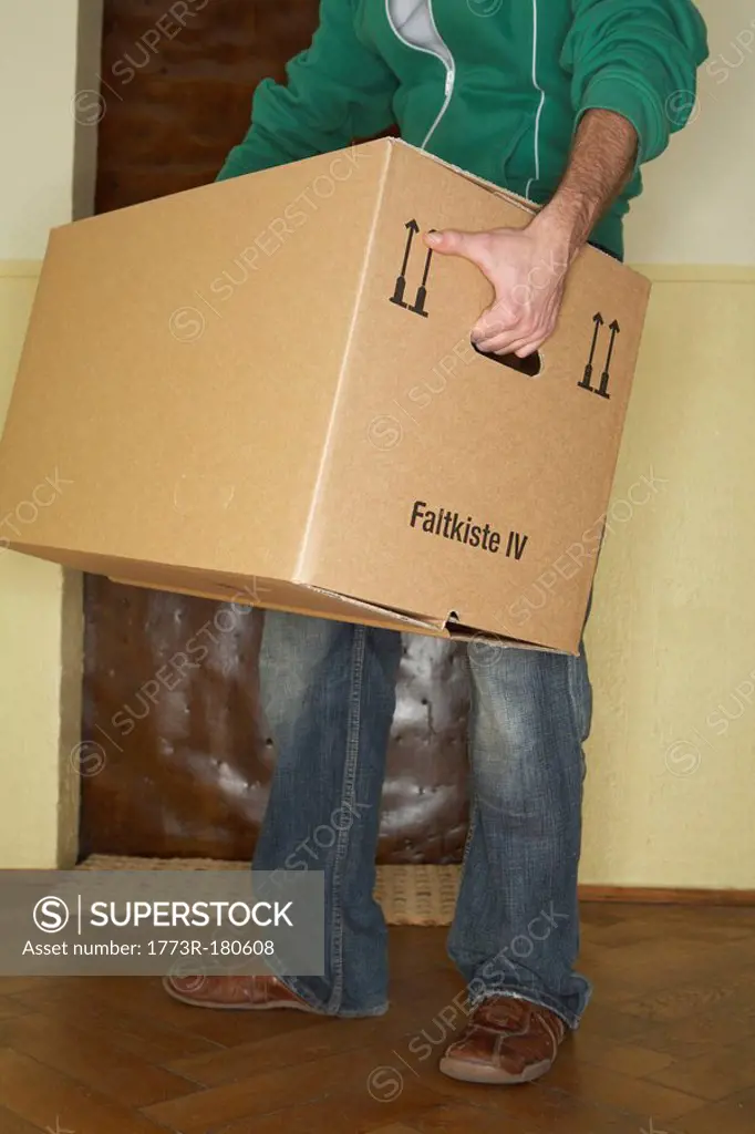 Young man carrying large cardboard box, low section