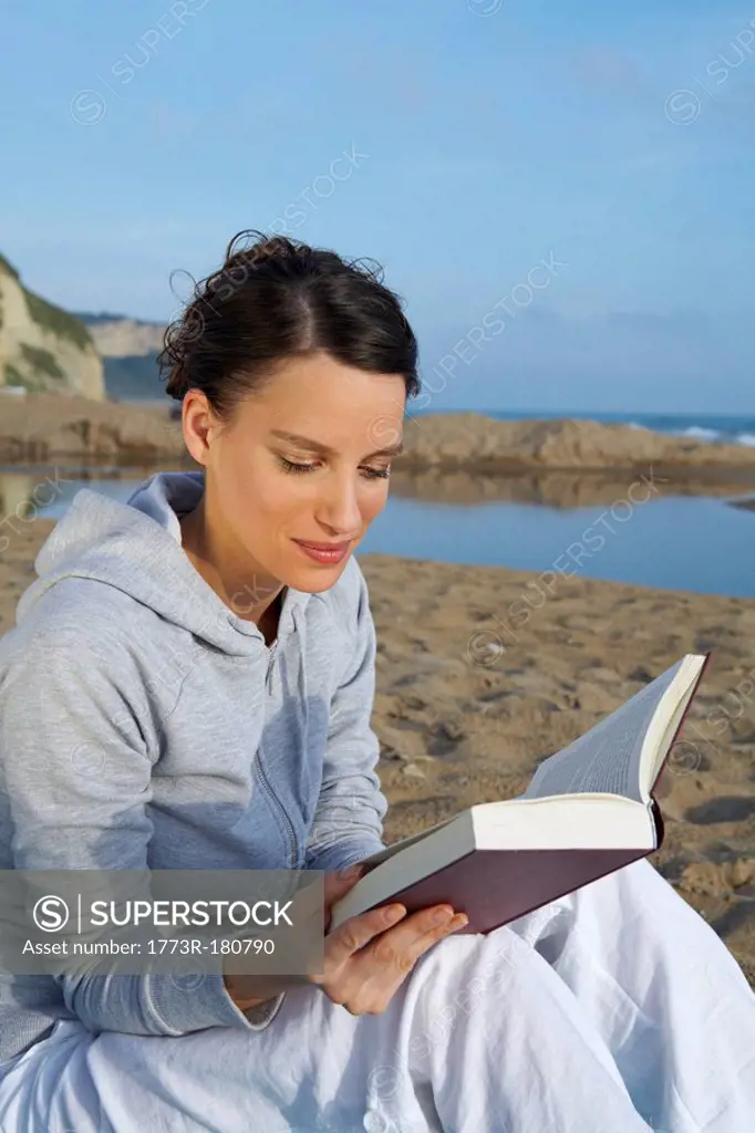 Young woman on beach portrait reading a book sea and sky in background
