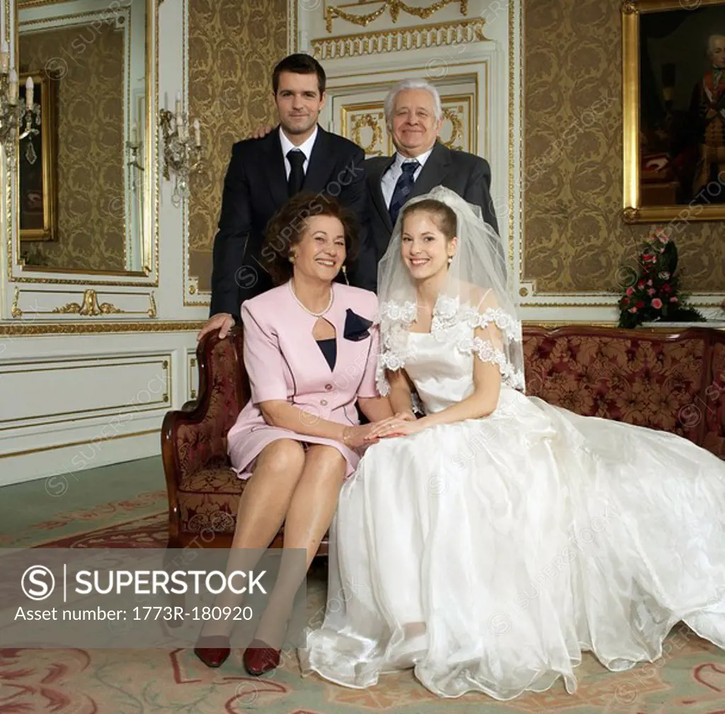 Bride and groom with parents, smiling, portrait