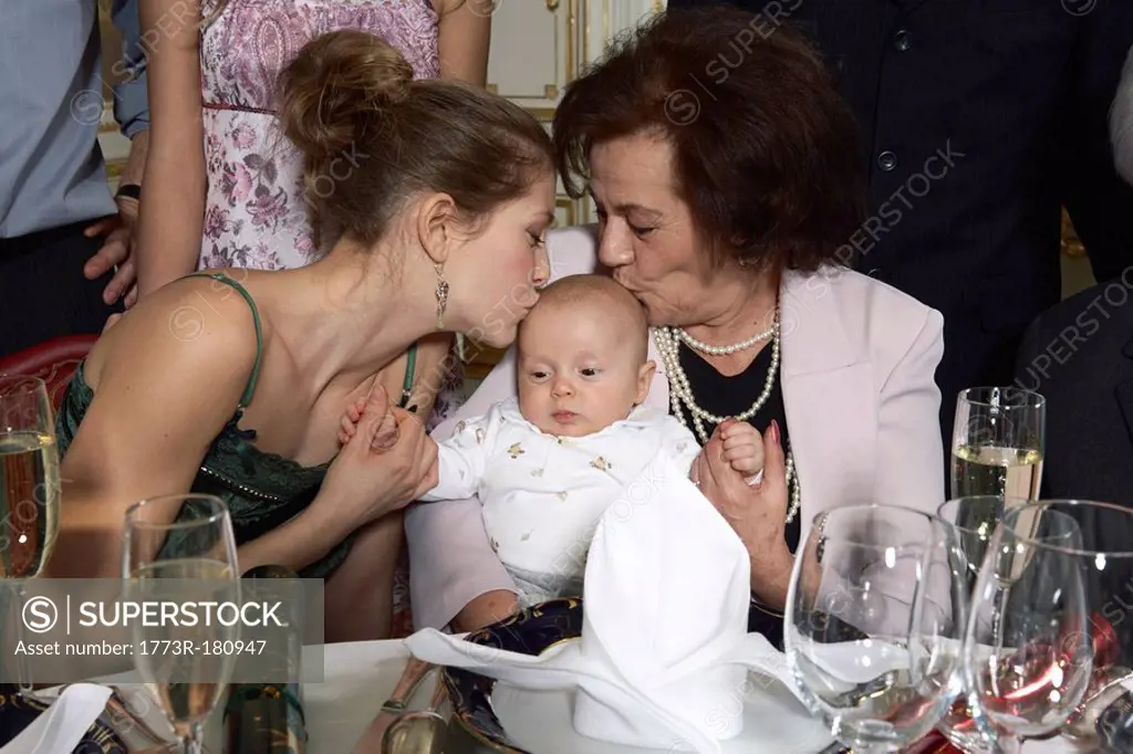 Young woman and senior woman kissing baby 3-6 month