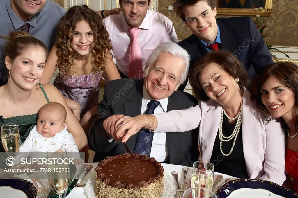 Grandparents with multigenerational family cutting cake