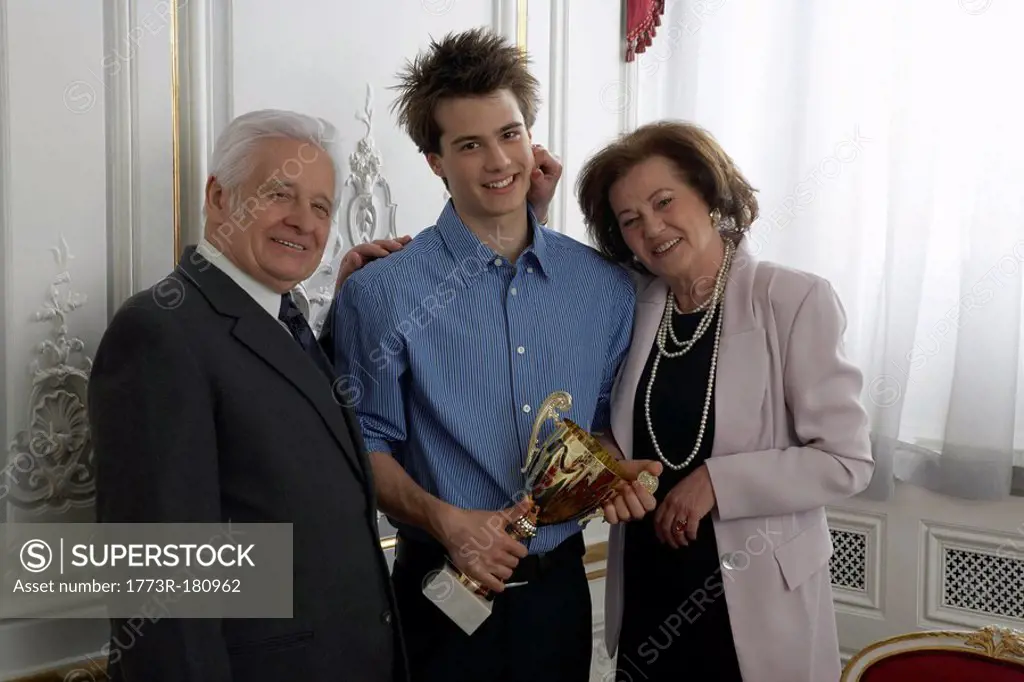 Grandparents presenting trophy to teenage boy 15-17 at family gathering