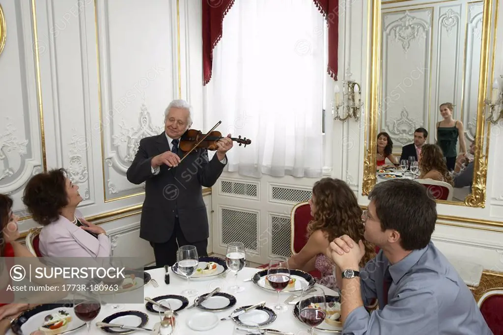 Senior man playing violin to family