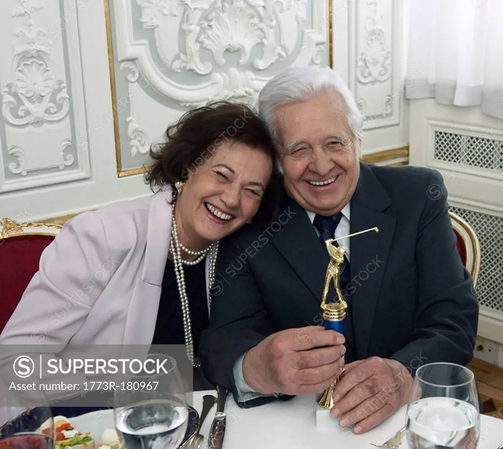 Senior couple with golf trophy, smiling, portrait