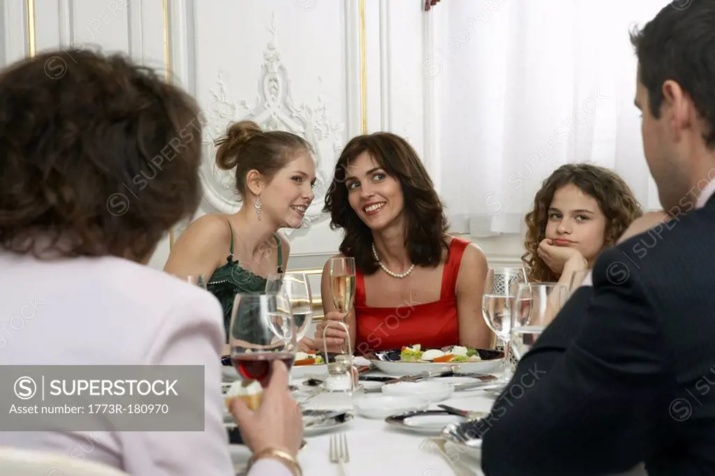 Two women talking at dinner table with family