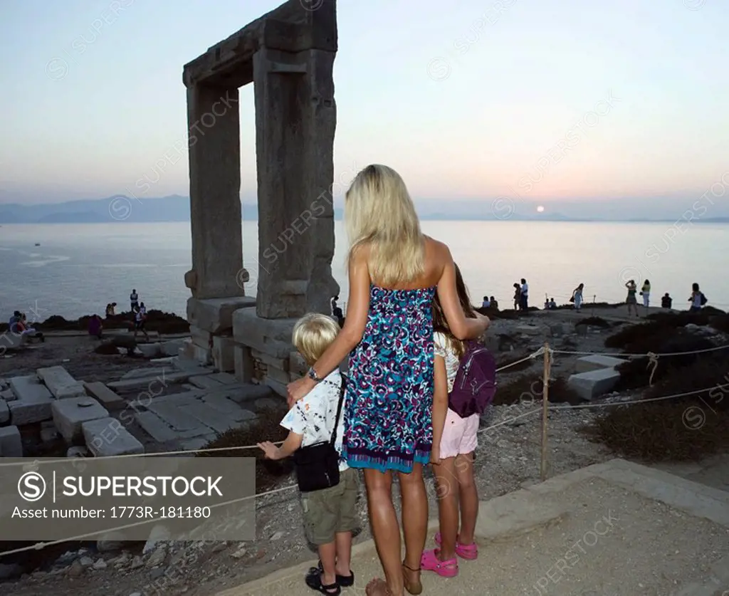Woman with young boy and young girl looking at The Portara in Greece with tourists in background
