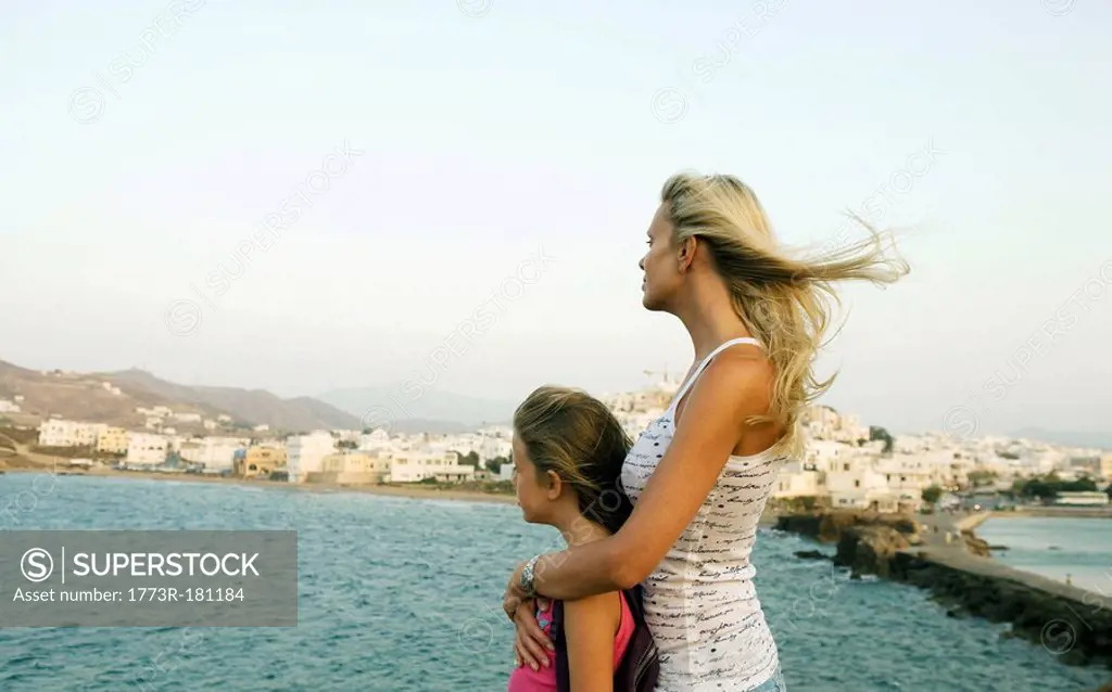 Woman and young girl looking over the water in Greece