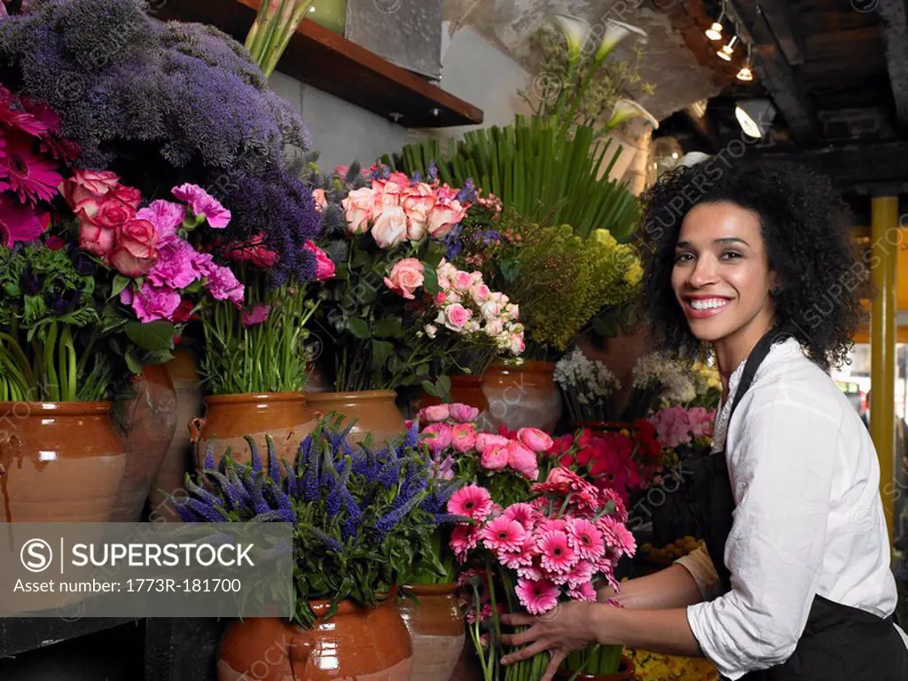 Young female florist holding flowers, smiling, portrait