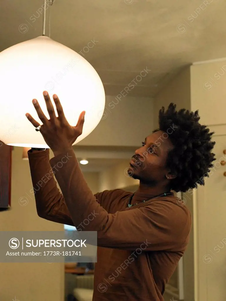 Man adjusting ceiling light in room