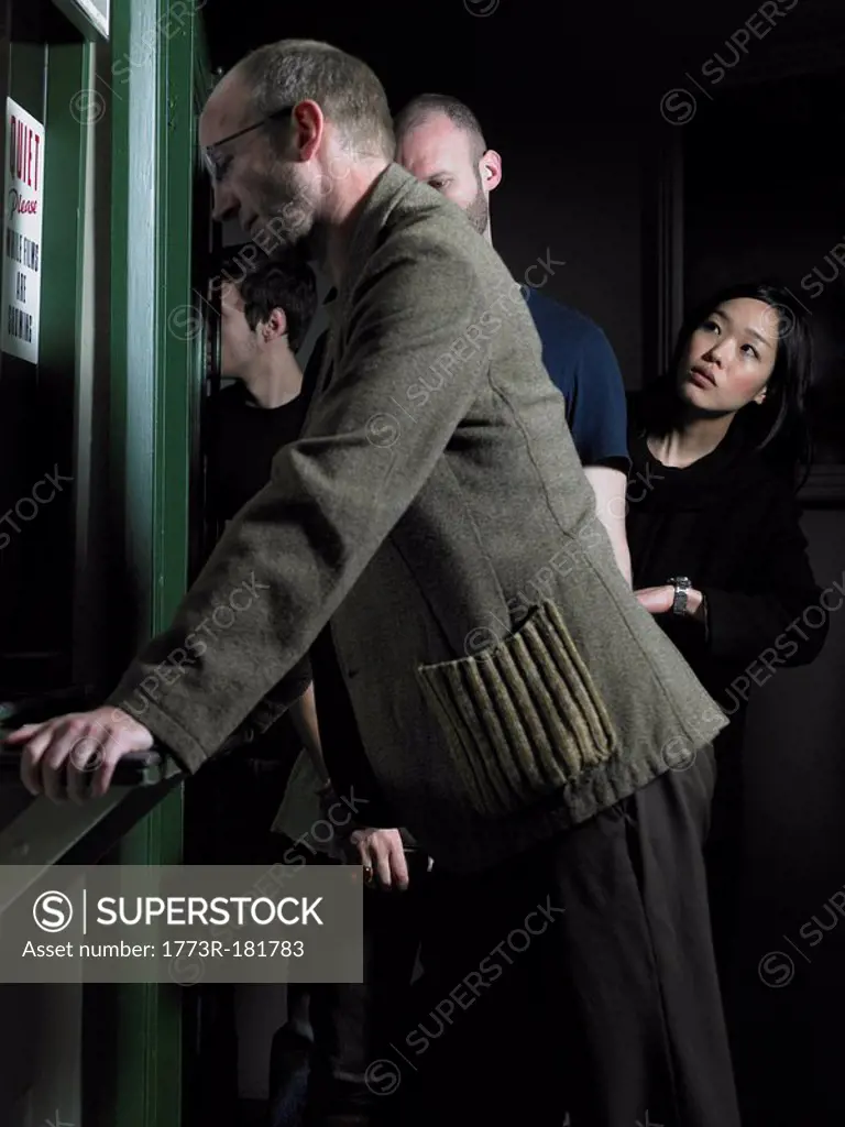 Man at counter, woman checking time in queue in background