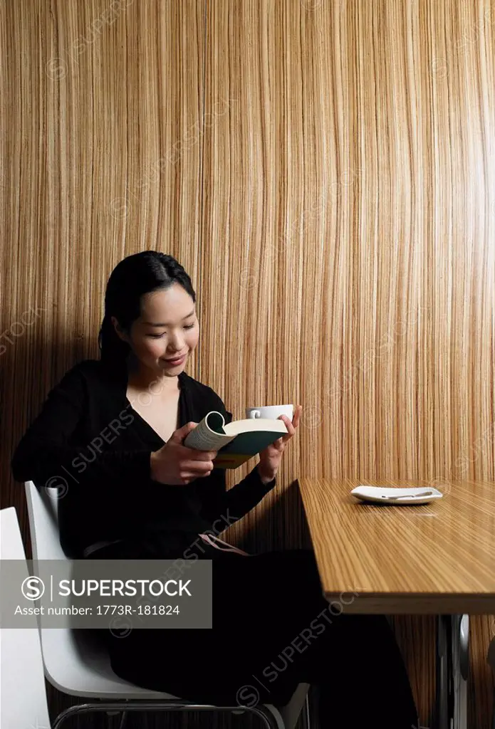 Young woman reading book in wood paneled café